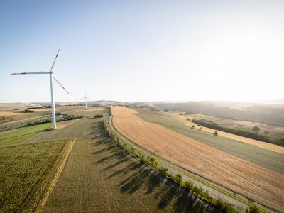 Wind power turbines stand in agricultural fields